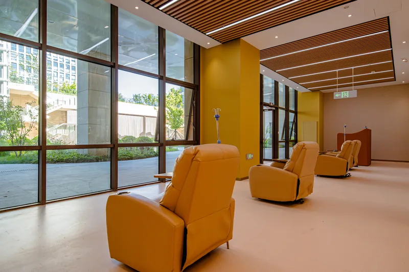 Reclining chairs and infusion stands beside garden-facing windows at Beijing Puhua International Hospital.